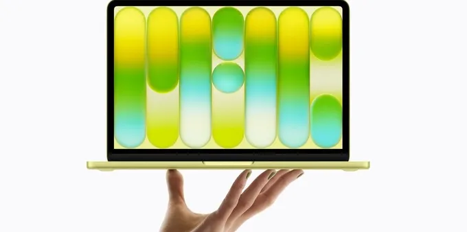 A hand holding the new MacBook Neo