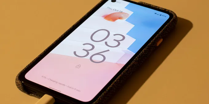 smartphone running android 12, showing the lockscreen while charging on a yellow table