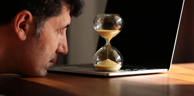 a man watching sand in an hourglass, concept of waiting